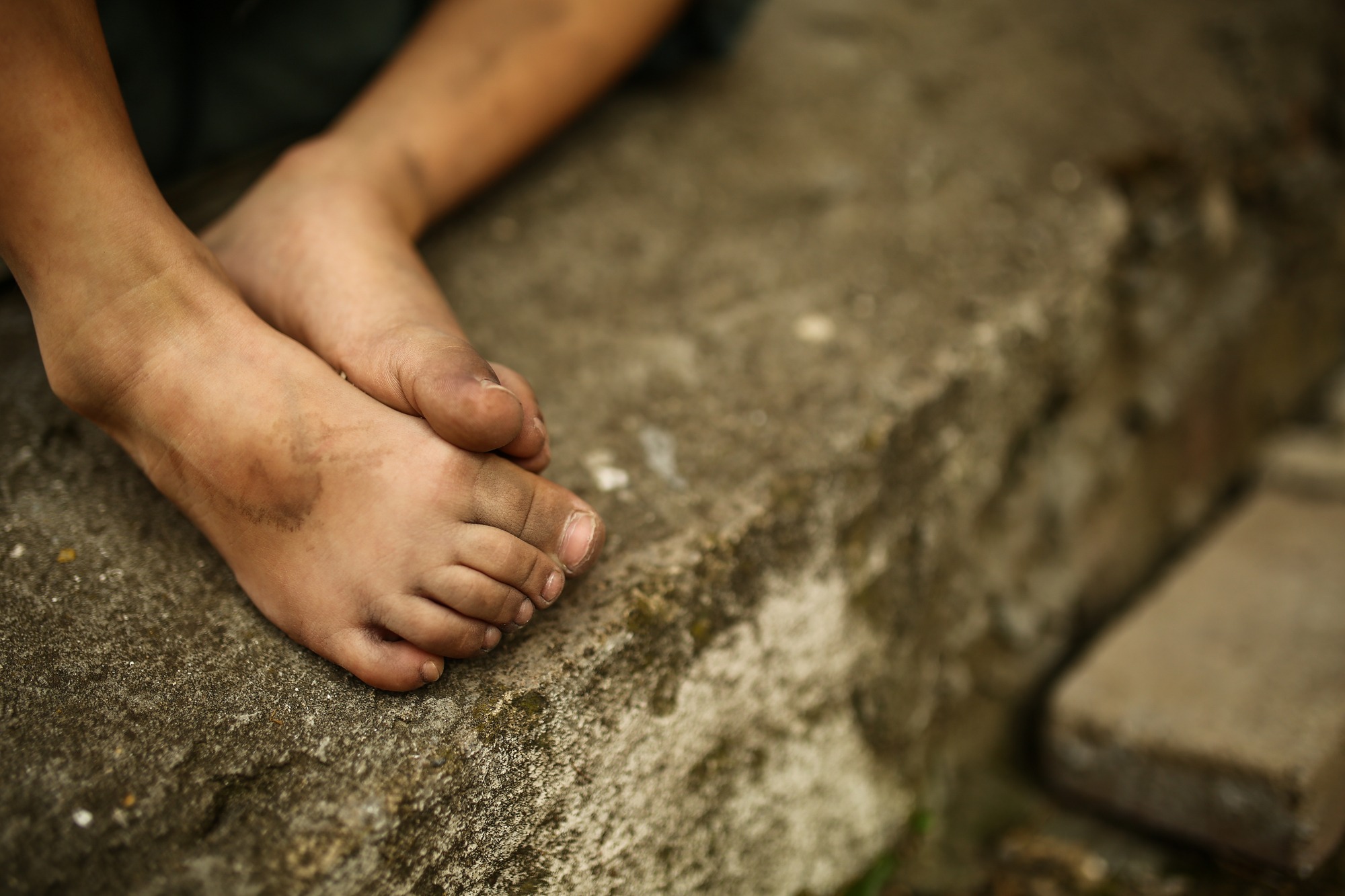 A person's bare feet positioned on a rough cement