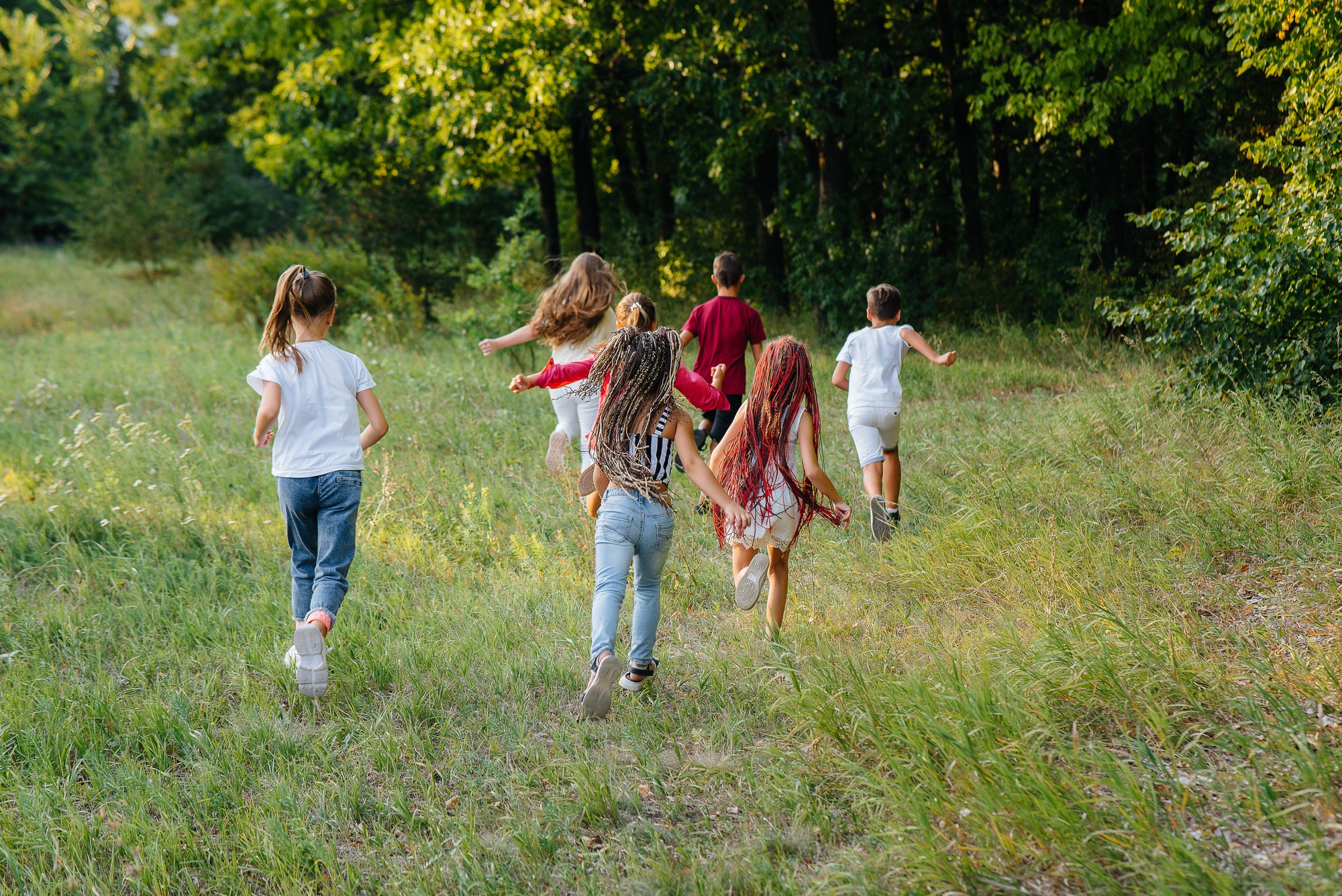 A group of children joyfully running through a lush green forest